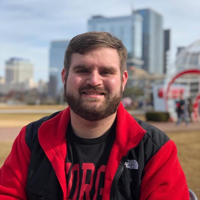 Headshot of Philip Peavy, white man with short light brown hair and beard, wearing a red fleece over a black t-shirt